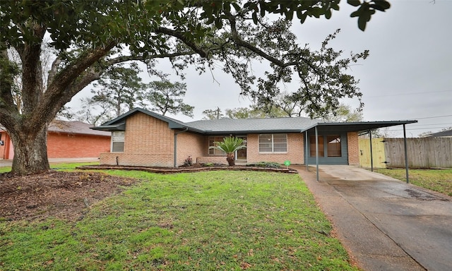 view of front of house with a front yard, fence, driveway, a carport, and brick siding