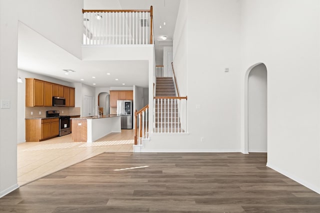 unfurnished living room featuring sink, light hardwood / wood-style flooring, and a high ceiling