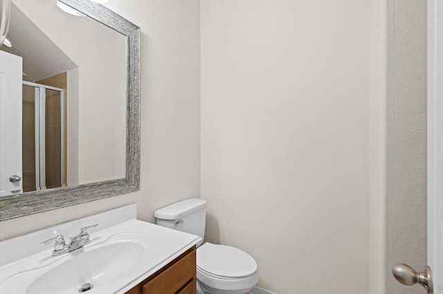 bathroom with vanity, toilet, and a shower with door