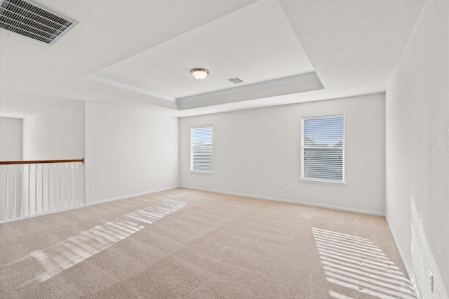 carpeted empty room featuring a tray ceiling