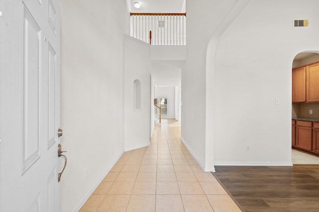 corridor with light tile patterned floors and a towering ceiling