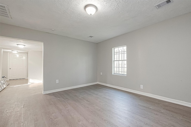 unfurnished room with light hardwood / wood-style floors and a textured ceiling