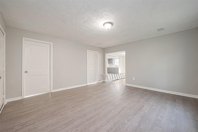 unfurnished room with a textured ceiling and light wood-type flooring