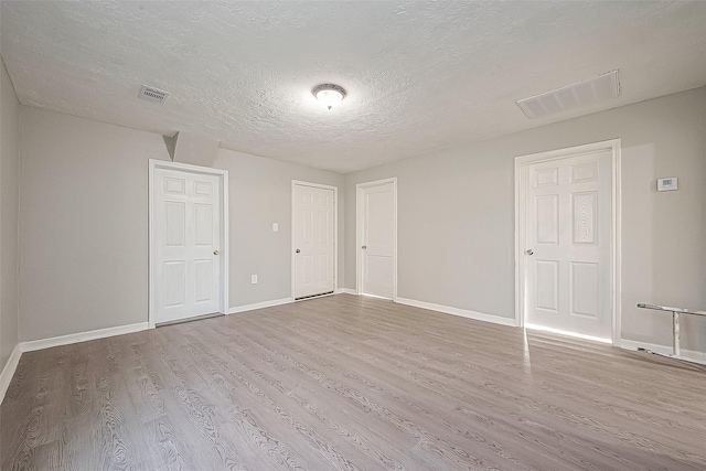 unfurnished room featuring light wood-type flooring and a textured ceiling