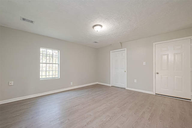 spare room featuring light hardwood / wood-style floors and a textured ceiling