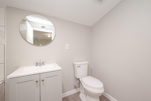 bathroom with vanity, toilet, and hardwood / wood-style flooring