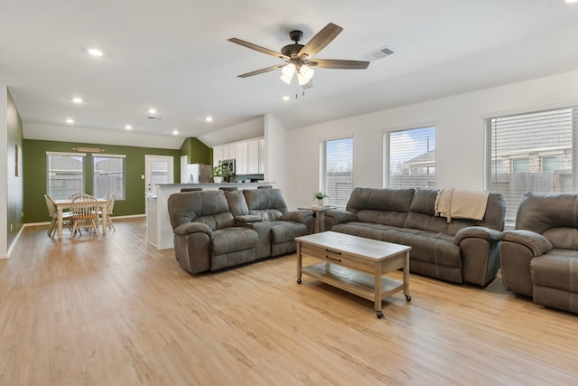 living room featuring vaulted ceiling, ceiling fan, and light wood-type flooring