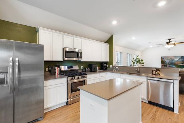 kitchen featuring vaulted ceiling, a kitchen island, white cabinets, kitchen peninsula, and stainless steel appliances