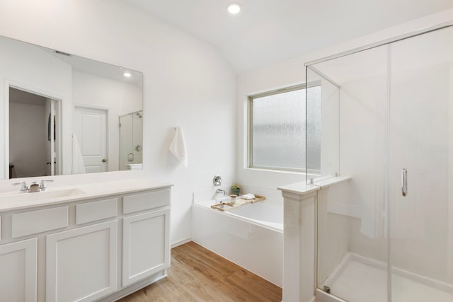 bathroom featuring vanity, hardwood / wood-style flooring, vaulted ceiling, and independent shower and bath