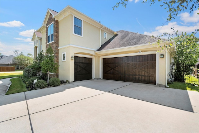 view of front of property with a garage, concrete driveway, roof with shingles, and stucco siding