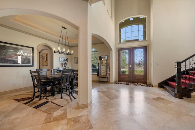 foyer entrance featuring a high ceiling, baseboards, ornamental molding, stairway, and a raised ceiling