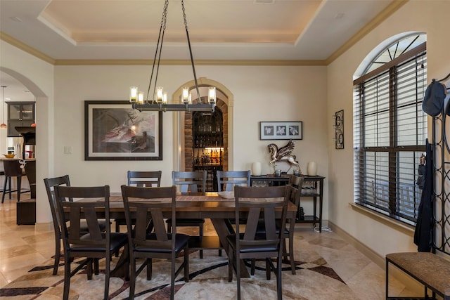 dining area featuring arched walkways, a raised ceiling, and crown molding