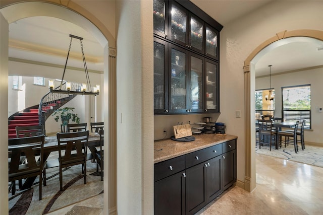 bar with an inviting chandelier, baseboards, arched walkways, and decorative light fixtures