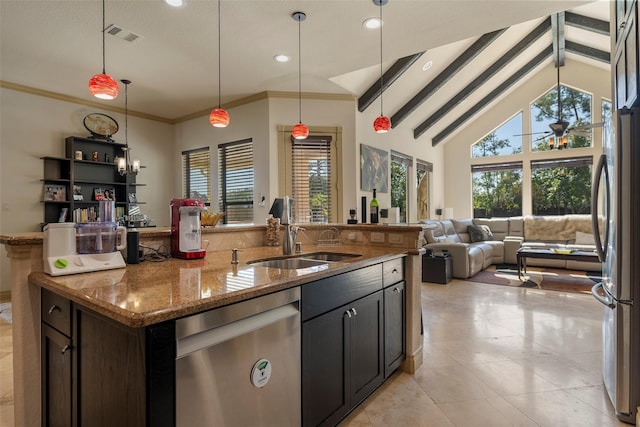 kitchen with stone countertops, a sink, open floor plan, appliances with stainless steel finishes, and beam ceiling