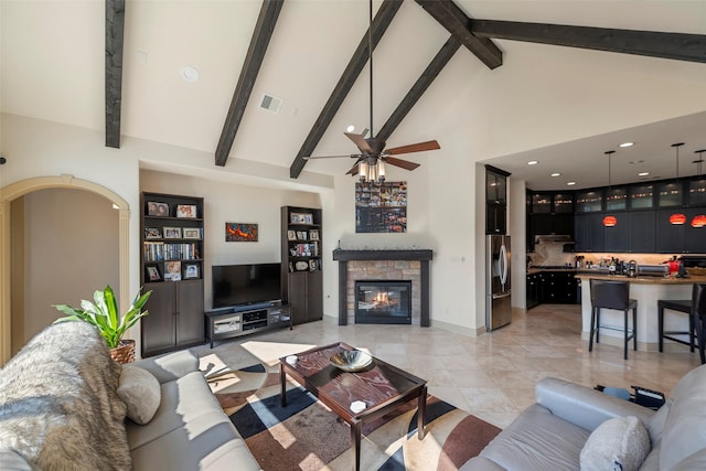 living room featuring ceiling fan, high vaulted ceiling, a stone fireplace, visible vents, and beam ceiling