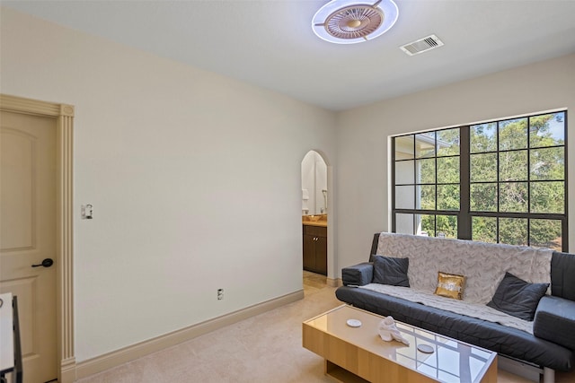 living room with light carpet, baseboards, visible vents, and arched walkways