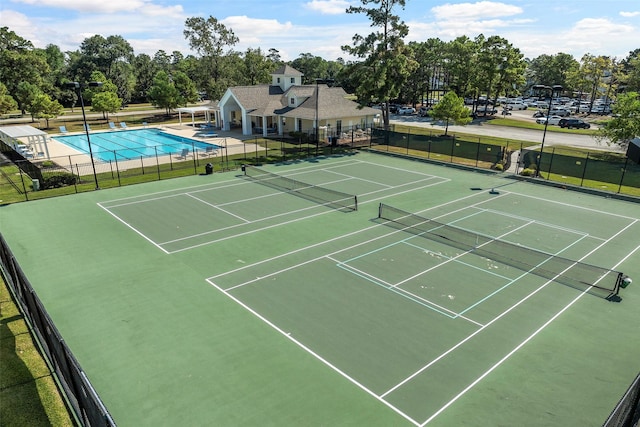 view of sport court with fence and a community pool