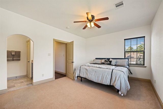 bedroom with visible vents, arched walkways, baseboards, light colored carpet, and ceiling fan