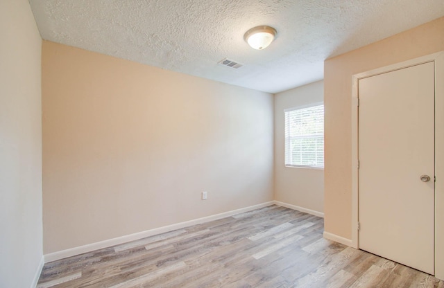 unfurnished bedroom with light wood-type flooring and a textured ceiling