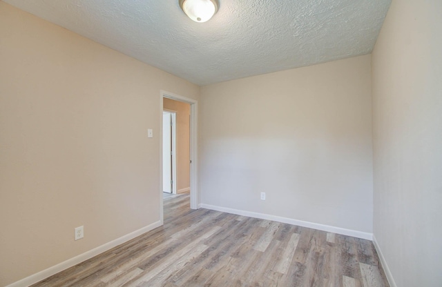 spare room featuring light wood-type flooring and a textured ceiling