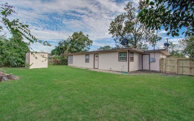 rear view of house with a yard and a storage shed