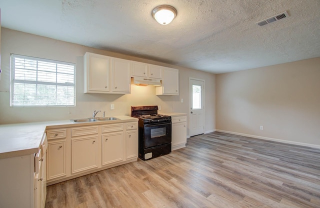 kitchen with black gas stove, sink, white cabinetry, a textured ceiling, and light hardwood / wood-style floors