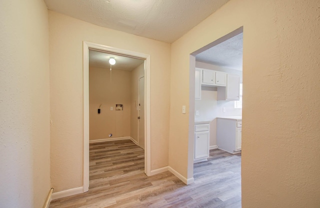 hallway with light hardwood / wood-style floors and a textured ceiling