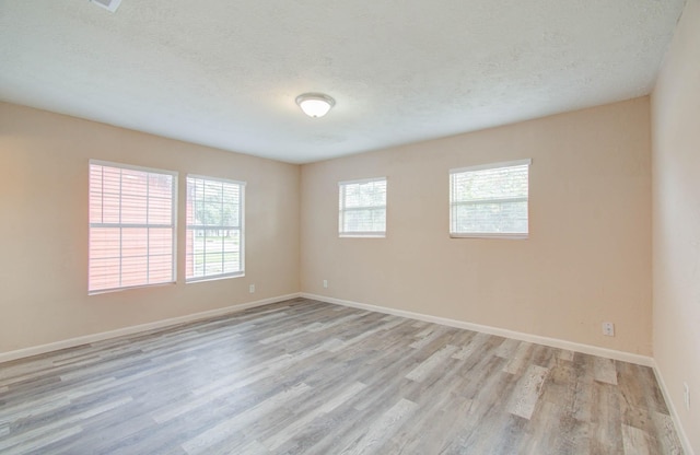 unfurnished room featuring light hardwood / wood-style floors and a textured ceiling