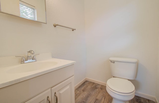 bathroom with hardwood / wood-style flooring, toilet, and vanity