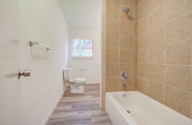 bathroom featuring tiled shower / bath combo, wood-type flooring, and toilet