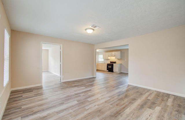 unfurnished room with light wood-type flooring and a textured ceiling