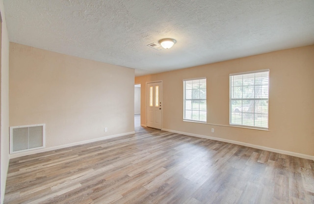 unfurnished room featuring light wood-type flooring and a textured ceiling