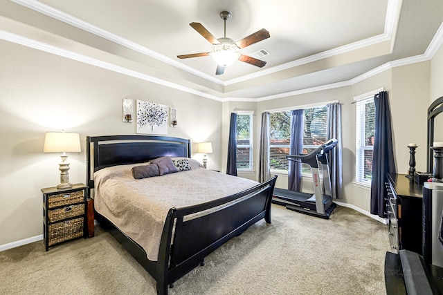 bedroom with ceiling fan, ornamental molding, light carpet, and a tray ceiling