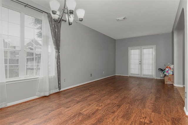 spare room with dark hardwood / wood-style floors, a notable chandelier, and french doors