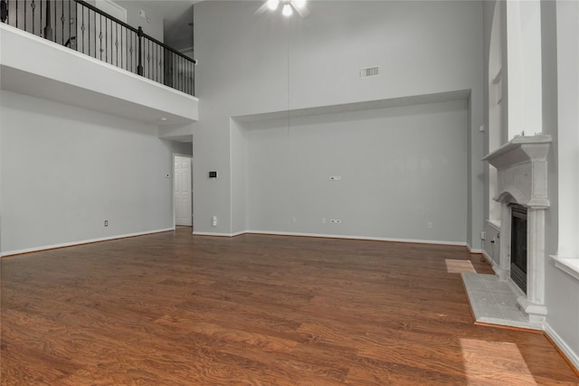 unfurnished living room featuring a high ceiling, a tile fireplace, and dark wood-type flooring