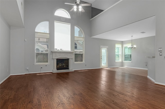 unfurnished living room featuring hardwood / wood-style flooring, ceiling fan with notable chandelier, and a towering ceiling