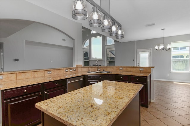 kitchen featuring hanging light fixtures, stainless steel dishwasher, sink, a kitchen island, and dark brown cabinets