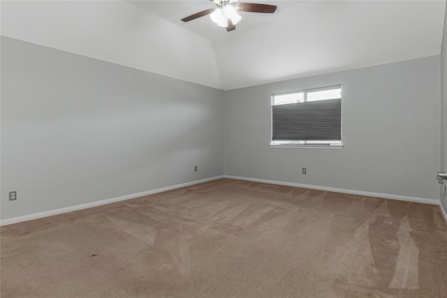 carpeted spare room featuring vaulted ceiling and ceiling fan