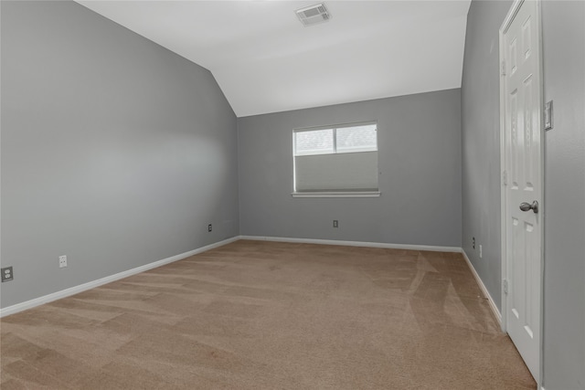 carpeted empty room featuring vaulted ceiling