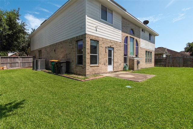 rear view of property featuring central air condition unit, a patio area, and a lawn