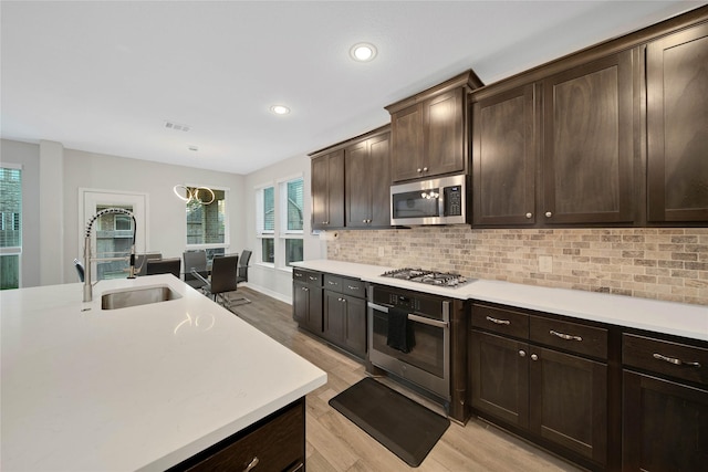 kitchen with stainless steel appliances, light hardwood / wood-style floors, sink, decorative backsplash, and dark brown cabinets