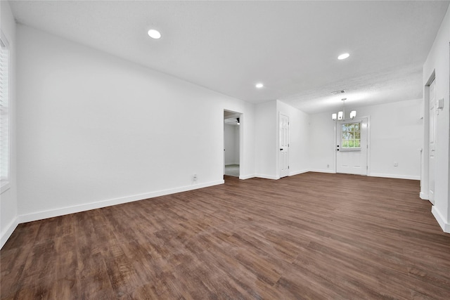 unfurnished living room featuring dark hardwood / wood-style floors and a notable chandelier