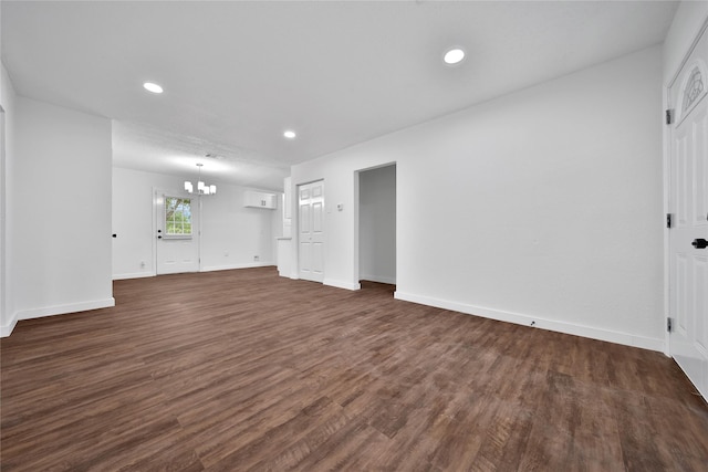 unfurnished living room with an inviting chandelier and dark hardwood / wood-style flooring