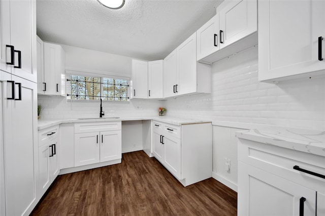 kitchen featuring a textured ceiling, white cabinets, sink, dark hardwood / wood-style floors, and light stone counters