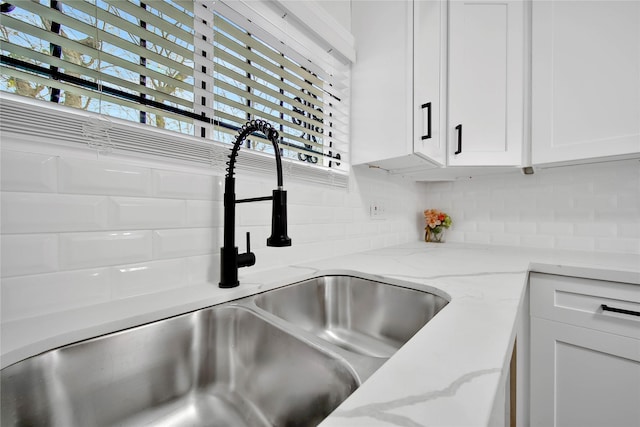 details with sink, white cabinets, and light stone counters