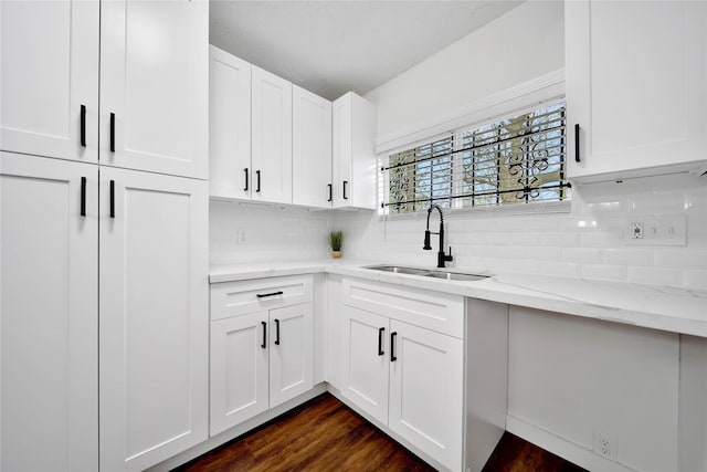 kitchen featuring tasteful backsplash, sink, white cabinets, dark hardwood / wood-style flooring, and light stone counters