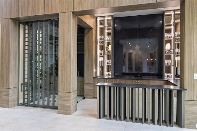 wine room featuring sink, wood walls, and light tile patterned floors