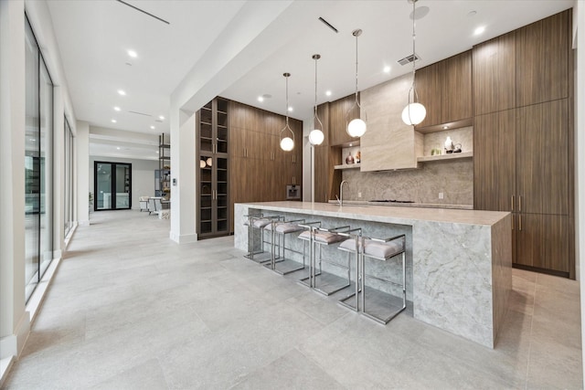 kitchen featuring pendant lighting, a large island, sink, wooden walls, and a breakfast bar area