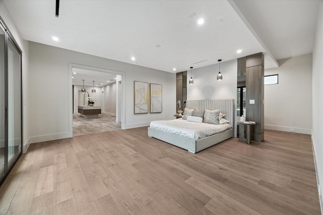 bedroom featuring light hardwood / wood-style floors, a closet, and ensuite bath