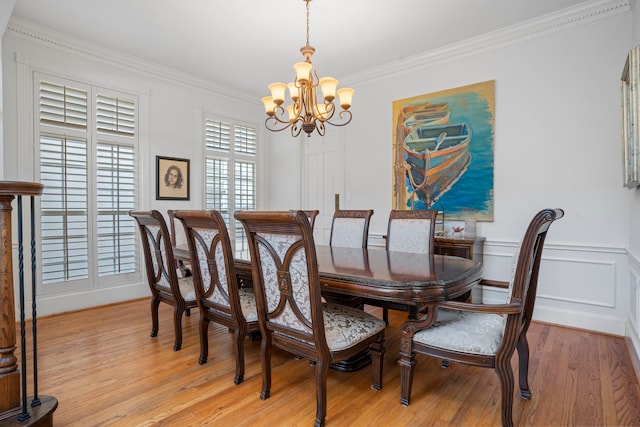 dining area with ornamental molding, light hardwood / wood-style flooring, and an inviting chandelier